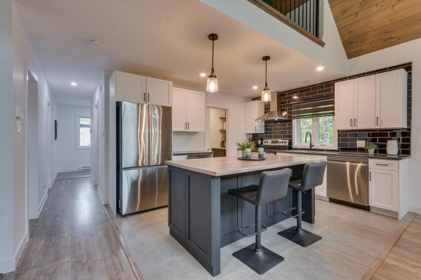 Open-concept kitchen and living area with an island, light wood floors, and vaulted ceiling. - 4 Ch. Des Contes, Notre Dame De Pontmain