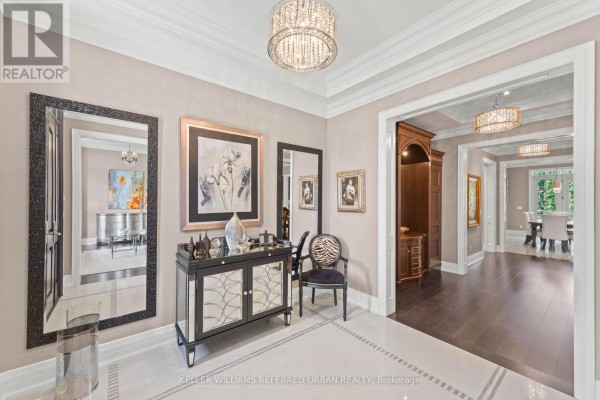 Foyer with a dark wood double door, mirrored cabinet, decorative chair, and a large crystal chandelier. - 4 Community Circle, Toronto