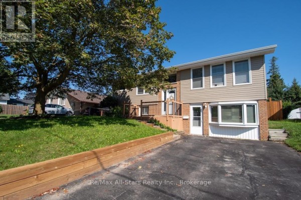 Wide exterior view of a split-level house with a large tree in the front yard. - 4 Daniel Court, Kawartha Lakes
