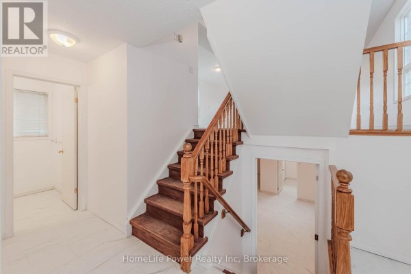 Staircase in the foyer with wooden railing and tiled flooring. - 4 Darling Crescent, Guelph