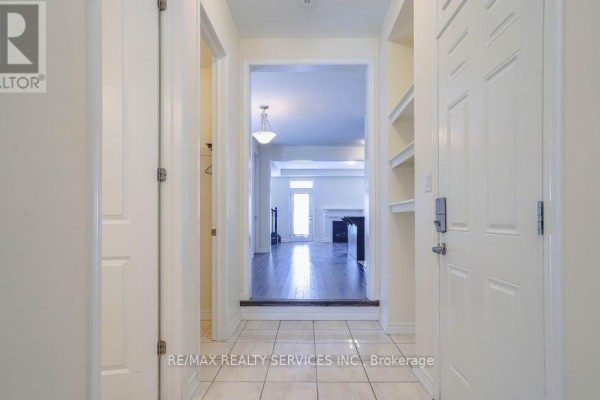 Tiled entryway with white doors and a view of a living room with a fireplace and dark wood floors. - 4 Divers Road, Brampton