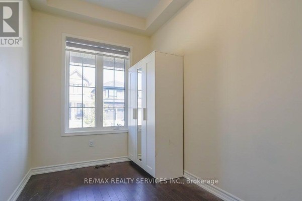 Small room with a large window overlooking houses, a white mirrored wardrobe, and dark wood flooring. - 4 Divers Road, Brampton