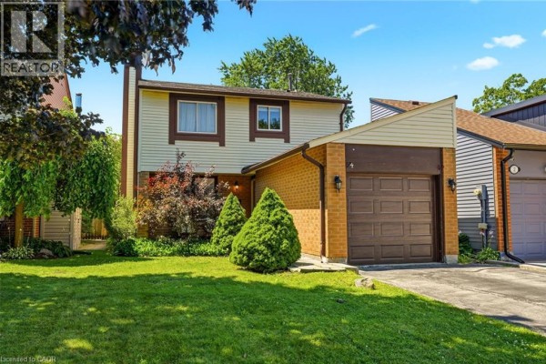 Front exterior of a two-story house with a tan facade and brick lower level. - 4 Eileen Street, Waterdown