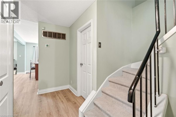 Interior hallway with a staircase, light green walls, and light wood flooring. - 4 Eileen Street, Waterdown