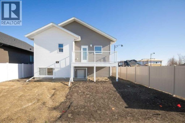 Back of the house showing a white deck and a partially landscaped yard with a fence. - 4 Emmett Crescent, Red Deer
