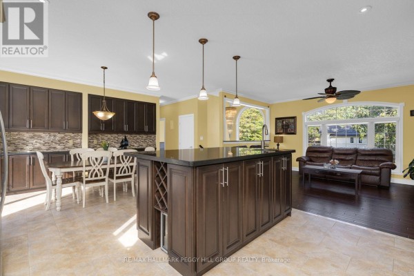 An open concept kitchen features dark wood cabinets, a large island with wine storage, and a seating area. - 4 Fatima Court, Wasaga Beach