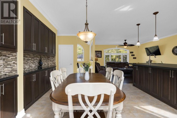 A formal dining area with a wooden table, white chairs, and extensive dark wood cabinetry is adjacent to the kitchen. - 4 Fatima Court, Wasaga Beach