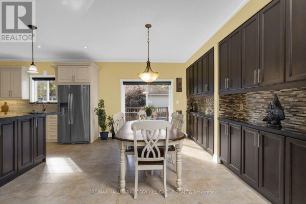 A dining area with a wooden table and chairs is situated between the kitchen, featuring stainless steel appliances, and a sliding glass door. - 4 Fatima Court, Wasaga Beach