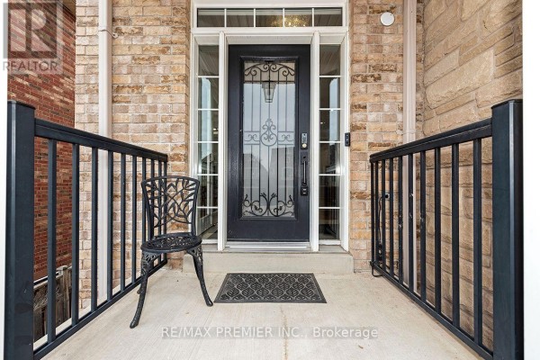 Front door with decorative glass and metalwork, flanked by black metal railings and a small black chair. - 4 George Mckenzie Court, Toronto