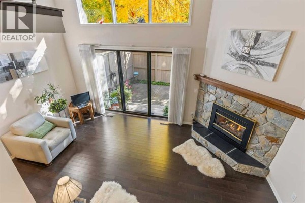 High-angle view of a living room with a fireplace and large windows showing autumn trees. - 4 Glamis Gardens Sw, Calgary