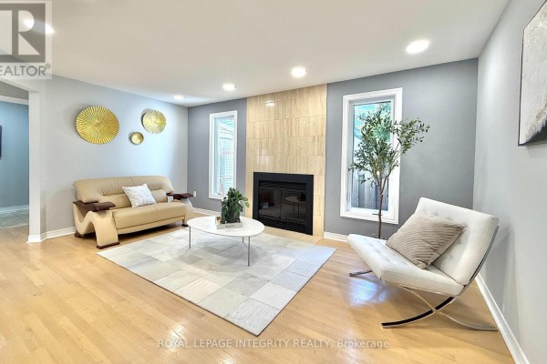 Living room with a gas fireplace, light wood floors, and modern furniture. - 4 Glenarden Court, Ottawa
