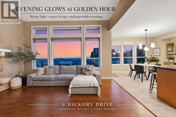 Living room featuring a stone fireplace, hardwood floors, a grey sofa, and large windows with a water view. - 4 Hickory Drive, Port Moody