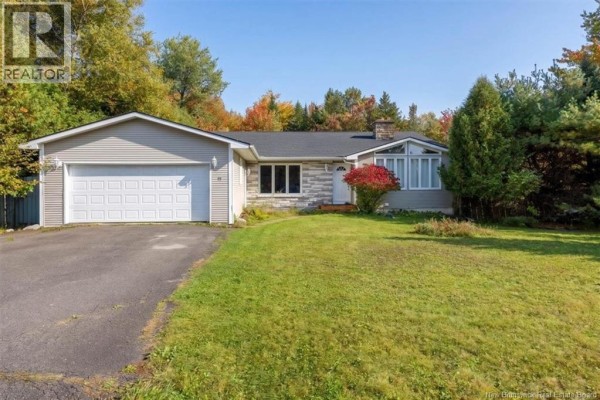 Exterior of a single-story house with a grey facade, white garage door, and green lawn. - 4 Hughes Crescent, Quispamsis
