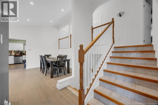 Interior view of a dining area with dark wood table, leading to a staircase. - 4 Hughes Crescent, Quispamsis