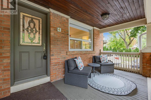 Front porch with dark grey outdoor furniture, a round rug, and a stained glass door. - 4 Kenrae Road, Toronto