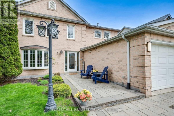 Front entrance detail with two blue chairs on a stone patio next to a double garage. - 4 Milgate Place, Aurora