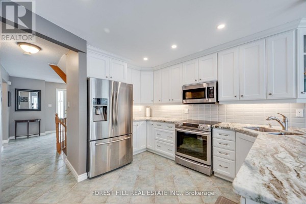 Kitchen view with stainless steel refrigerator, white cabinets, granite countertops, and a stove. - 4 Milgate Place, Aurora