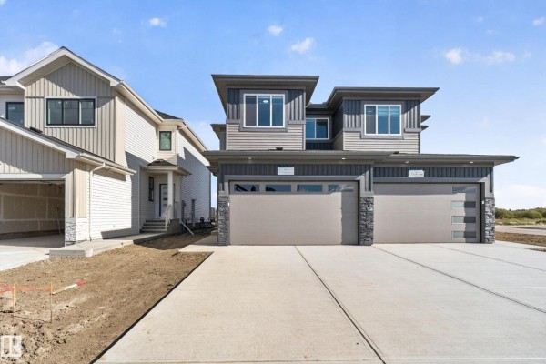Front exterior of a duplex with grey siding, dark trim, and double garages. - 4 Parker Ln, Spruce Grove