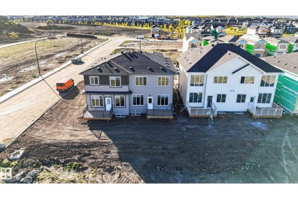 Rear view of two duplexes with grey and white siding and wooden decks. - 4 Parker Ln, Spruce Grove