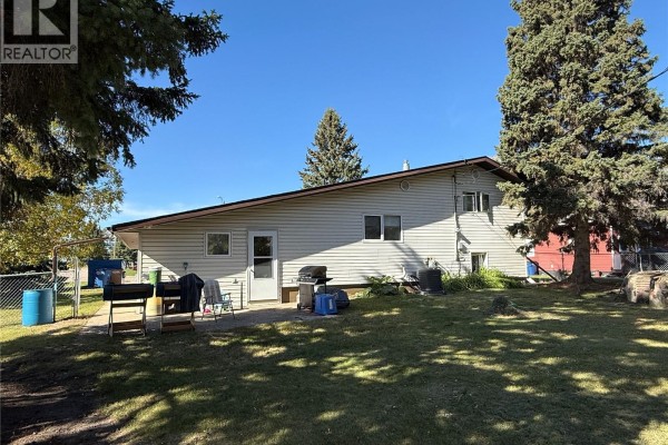 Rear exterior of the house with a patio, green lawn, and mature trees. - 4 Pepper Place, Shellbrook