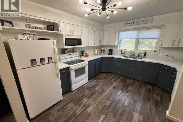 Kitchen with white countertops, white and dark blue cabinets, and a white stove. - 4 Pepper Place, Shellbrook