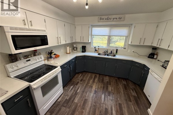 Kitchen with white countertops, white and dark blue cabinets, and a white stove. - 4 Pepper Place, Shellbrook