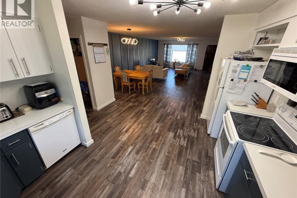 View from kitchen into dining area with wooden table and living room with sofas. - 4 Pepper Place, Shellbrook