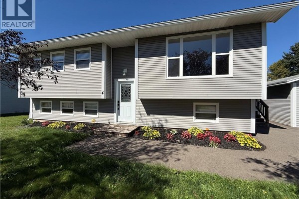 View of the front of the grey split-level house with a paved walkway and flower beds. - 4 Phillips Street, Sussex Corner