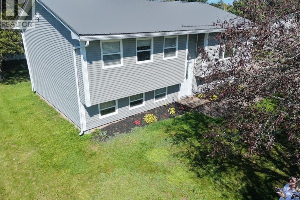 Aerial view of the grey split-level house exterior with green lawn and mature trees. - 4 Phillips Street, Sussex Corner