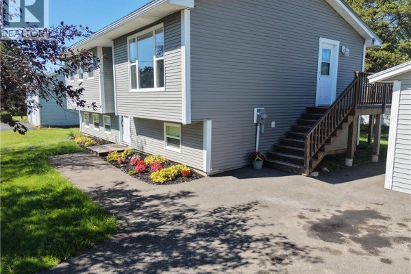 Side view of the grey split-level house showing wooden stairs leading to an elevated back door. - 4 Phillips Street, Sussex Corner