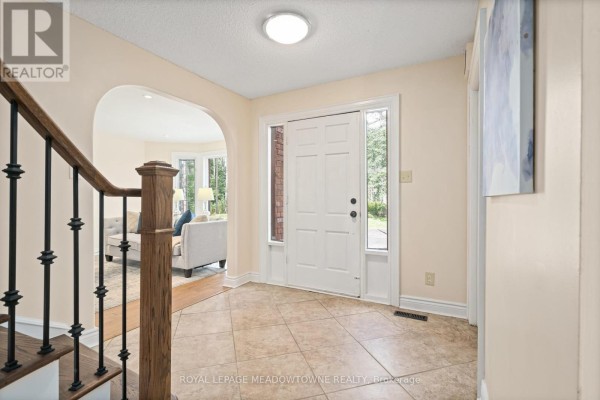 Interior view of a bright foyer with a staircase, archway, and tiled floor. - 4 Pine Ridge Road, Erin