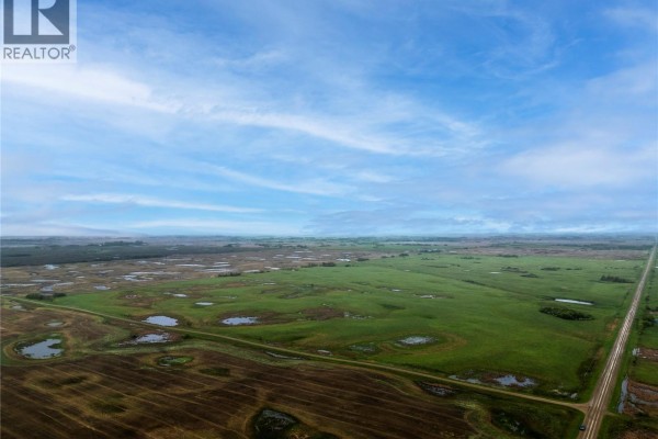 Aerial view of a large farm property with fields, roads, and numerous small ponds under a dramatic sky. - 4 Quarters - Melville, Grayson Rm No  184