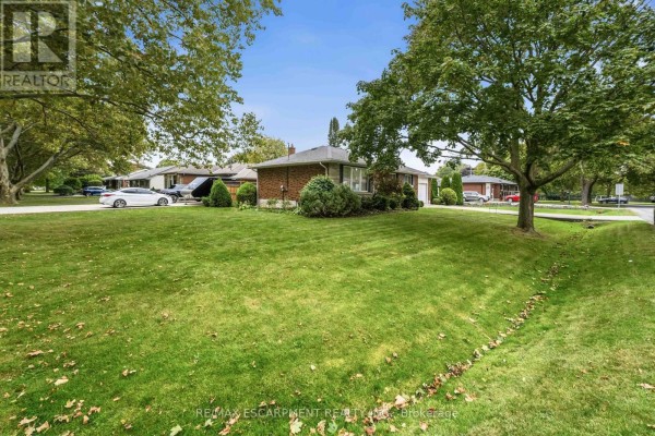 Side view of a residential property with a large green lawn and mature trees. - 4 Regina Avenue, St  Catharines