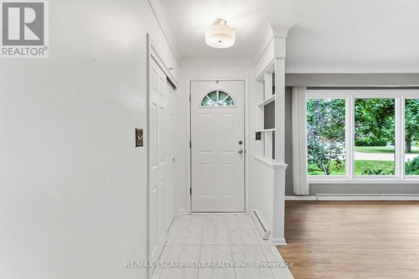 Interior entryway with white walls, tiled floor, white door, and adjacent living room. - 4 Regina Avenue, St  Catharines