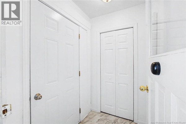 Interior hallway with white doors and trim, and light-colored patterned flooring. - 4 River Street, Fredericton