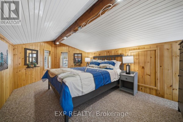 Bedroom with wood walls, vaulted ceiling, and lake bedding - 4 Stackwall Lane Greater Madawaska