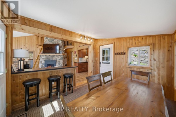 Stone fireplace with TV, bar with stools, and dining table - 4 Stackwall Lane Greater Madawaska