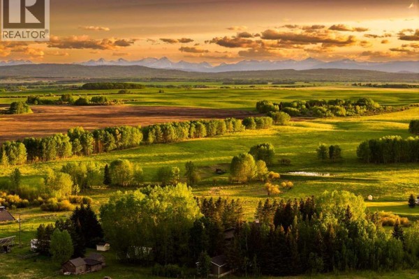 A weathered wooden fence and gate stand in a dry, grassy field under a cloudy sky. - 4 West Meadows Estates Road, Rural Rocky View County