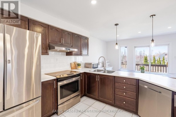 Modern kitchen with white tile floors, dark wood cabinets, stainless steel appliances, and a white island. - 4 Whispering Pine Place, Barrie