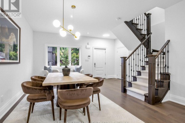 View of dining area with a wood table, velvet chairs, and a staircase with dark wood. - 4 Woodville Avenue, Toronto
