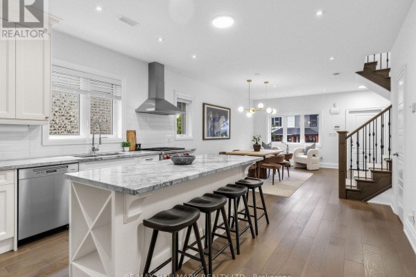 Kitchen island with marble countertop and bar stools, overlooking the dining and living area. - 4 Woodville Avenue, Toronto