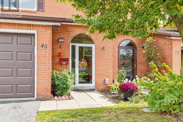 Detail of townhouse entrance with arched glass doors, brick facade, and potted plants. - 40 - 90 Crockamhill Drive, Toronto