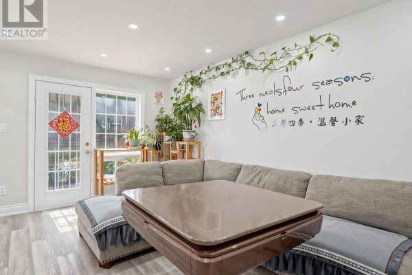 Living area with a sectional sofa, low table, plants, and white wall art. - 40 - 90 Crockamhill Drive, Toronto