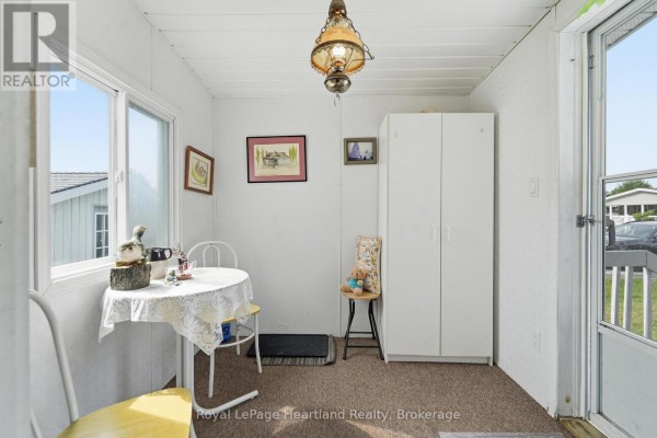 Sunroom with a round table, chairs, a large white cabinet, and a window with a view of the exterior. - 40 Algonquin Lane, Ashfield Colborne Wawanosh