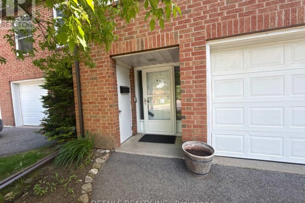 Close-up of townhouse entrance with red brick exterior, white door, and garage. - 40 Appleby Private, Ottawa