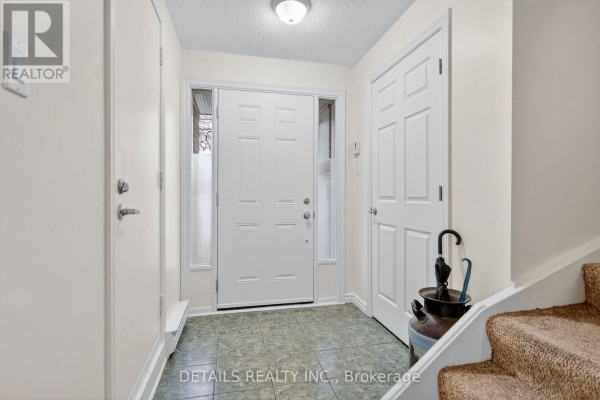 Foyer with white front door, tile floor, and staircase railing. - 40 Appleby Private, Ottawa
