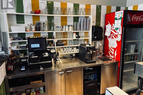Counter area with cash register, coffee machine, and glassware storage. - 40 Bolton Street, Kawartha Lakes