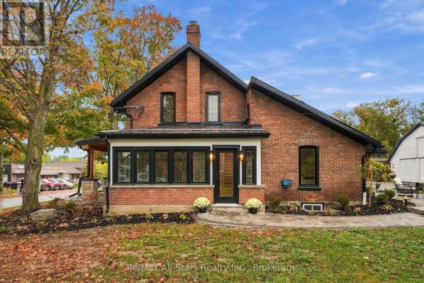 Close-up view of the brick house entrance with a sunroom, black windows, and fall leaves. - 40 Caroline Street, Kawartha Lakes