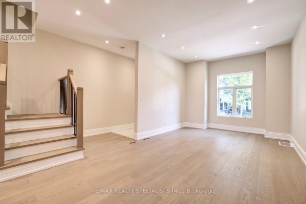 Living room showing stairs leading up, hardwood floors, and a window. - 40 Century Street, Hamilton
