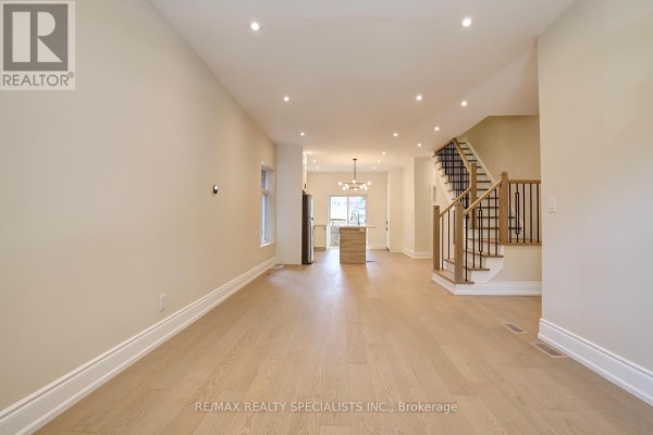 Open-concept interior showing living area, dining area, and kitchen with stairs. - 40 Century Street, Hamilton